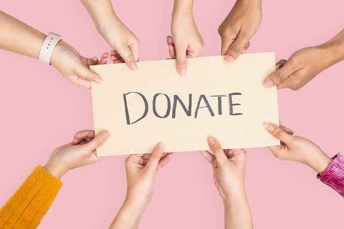 Several hands hold a card bearing the word donate.